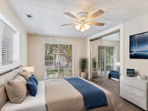 Carpeted bedroom featuring ceiling fan and a closet