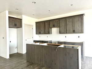 Kitchen featuring dark hardwood / wood-style flooring, dark brown cabinets, a textured ceiling, and a center island