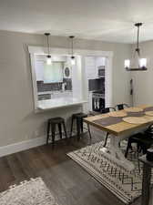 Dining space with sink, a textured ceiling, a chandelier, and dark wood-type flooring