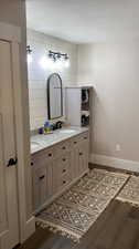 Bathroom with double vanity, a textured ceiling, and hardwood / wood-style floors