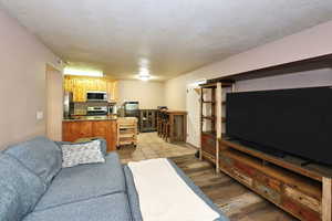 Living room with light hardwood / wood-style floors, sink, and a textured ceiling