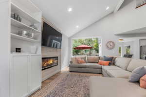 Living room featuring a large fireplace, high vaulted ceiling, and light wood-type flooring