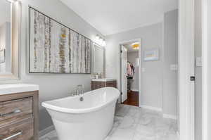 Primary bathroom with vanity, a tub to relax in, and tile patterned flooring