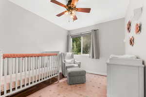 Bedroom featuring hardwood / wood-style flooring, a nursery area, and ceiling fan