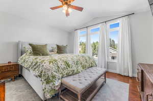 Primary bedroom featuring ceiling fan, hardwood / wood-style flooring, and lofted ceiling