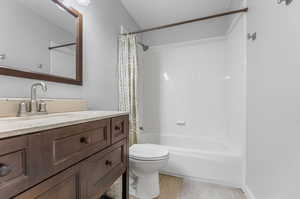 Full bathroom featuring shower / tub combo with curtain, vanity, hardwood / wood-style flooring, and toilet