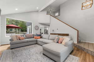 Living room with hardwood / wood-style flooring, beamed ceiling, a chandelier, and high vaulted ceiling