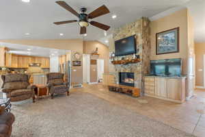 Tiled living room featuring a stone fireplace, vaulted ceiling,