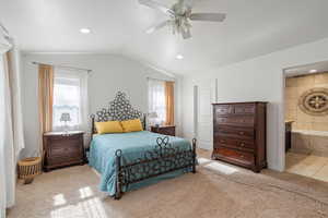 Primary bedroom with ensuite bathroom, ceiling fan, and vaulted ceiling