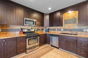 2nd Kitchen with light tile patterned flooring, decorative backsplash, appliances with stainless steel finishes.