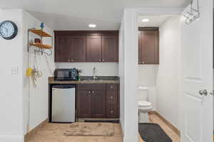 Wet Bar with sink, mini fridge light tile, dark brown cabinetry