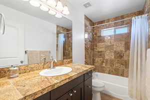 Full bathroom with toilet, shower / bathtub combination with curtain, and vanity