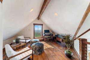 Interior space with hardwood / wood-style flooring and lofted ceiling with beams