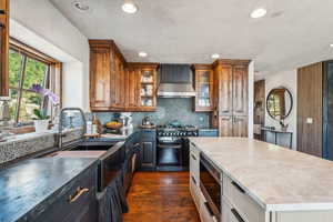 Kitchen featuring range with two ovens, built in microwave, decorative backsplash, wall chimney exhaust hood, and dark wood-type flooring