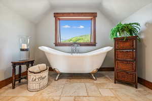 Bathroom with tile patterned floors, a bathtub, and vaulted ceiling