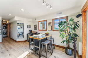 Dining space featuring stacked washer and clothes dryer, rail lighting, and light wood-type flooring