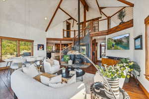 Living room featuring high vaulted ceiling, hardwood / wood-style floors, and a wood stove