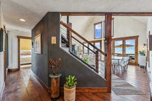 Staircase featuring wood-type flooring, high vaulted ceiling, and plenty of natural light