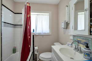 Full bathroom with vanity, shower / tub combo, and toilet