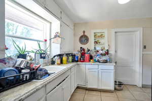 Kitchen with white cabinets, sink, and light tile patterned floors