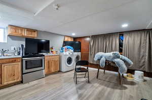 Kitchen featuring sink, washing machine and dryer, electric range, and light hardwood / wood-style floors