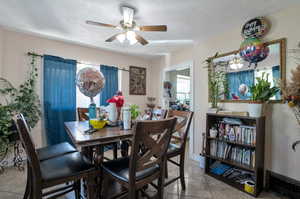 Dining space featuring light tile patterned flooring, a textured ceiling, and ceiling fan