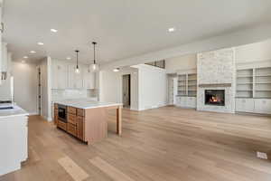 Kitchen with tasteful backsplash, decorative light fixtures, white cabinets, a kitchen island, and stainless steel microwave