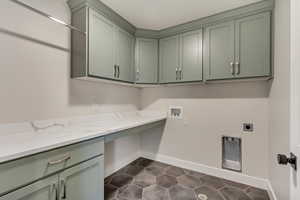 Washroom featuring hookup for an electric dryer, cabinets, dark tile patterned floors, and hookup for a washing machine