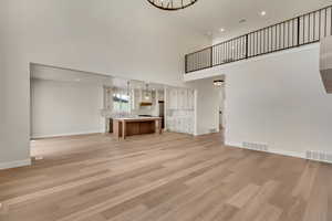 Unfurnished living room with a high ceiling, light wood-type flooring, and sink