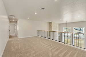 Spare room featuring a chandelier, a textured ceiling, and light colored carpet