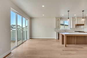 Kitchen featuring stainless steel range, sink, hanging light fixtures, tasteful backsplash, and light hardwood / wood-style floors