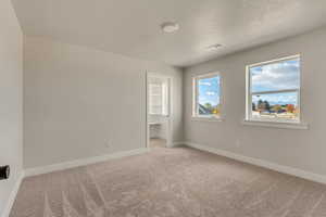 Unfurnished bedroom with light colored carpet, a textured ceiling, and a closet