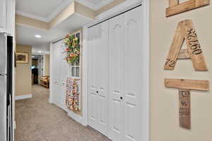 Corridor with light colored carpet and ornamental molding