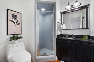 Bathroom featuring hardwood / wood-style flooring, vanity, toilet, and a shower with shower door