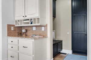 Interior space with white cabinetry, backsplash, and light wood-type flooring