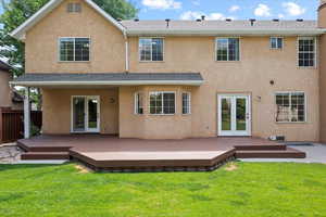 Back of house featuring french doors, a lawn, and a deck