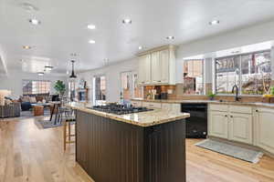 Kitchen featuring stainless steel gas stovetop, black dishwasher, light hardwood / wood-style flooring, and cream cabinetry