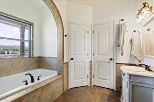 Bathroom with tiled tub, vanity, and tile patterned floors