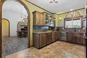 Kitchen with tasteful backsplash, sink, light hardwood / wood-style floors, decorative light fixtures, and a chandelier