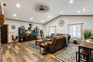 Living room with ornamental molding, lofted ceiling, hardwood / wood-style flooring, and ceiling fan