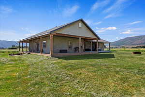 Back of property featuring a mountain view, a patio, and a lawn