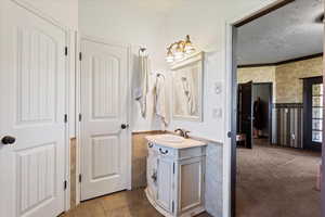 Bathroom featuring vanity, a textured ceiling, crown molding, and tile patterned flooring