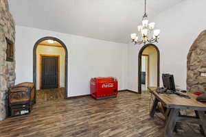 Office space featuring dark wood-type flooring, a chandelier, and lofted ceiling