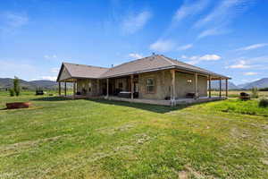 Back of property featuring a mountain view and a yard