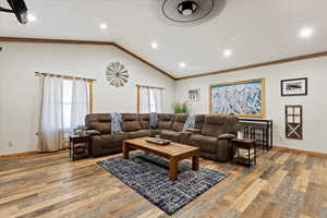 Living room featuring light hardwood / wood-style flooring, crown molding, and vaulted ceiling