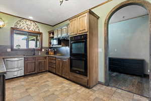 Kitchen with stainless steel dishwasher, tasteful backsplash, sink, light hardwood / wood-style floors, and double oven