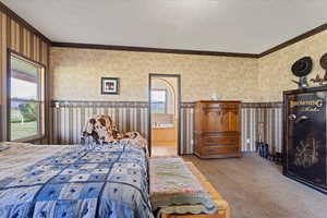 Bedroom with carpet floors, ensuite bathroom, and crown molding