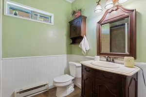 Bathroom featuring tile patterned flooring, toilet, a baseboard radiator, and vanity