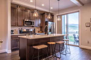 Kitchen featuring refrigerator, dark hardwood / wood-style floors, stove, and a kitchen island with sink