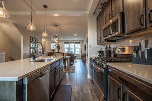 Kitchen with beamed ceiling, stainless steel appliances, backsplash, an island with sink, and dark wood-type flooring